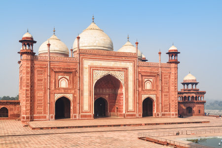 The Kau Ban Mosque of the Taj Mahal complex on blue sky background in Agra, India. Amazing red sandstone building reflected in water of pool. Wonderful Mughal architecture.の写真素材
