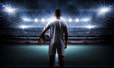 Football player with ball on field of stadium. The imaginary football stadium is modeled and rendered.の写真素材