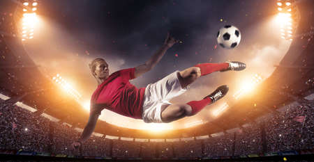 Soccer player in action on stadium background.The imaginary soccer stadium is modeled and rendered.の写真素材