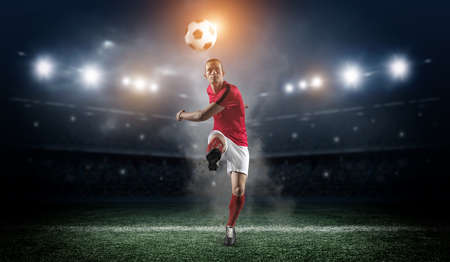 Soccer player in action on stadium background.The imaginary football stadium is modeled and rendered.の写真素材