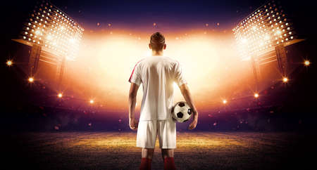 Football player with ball and stadium, an imaginary stadium is modeled and rendered.の写真素材