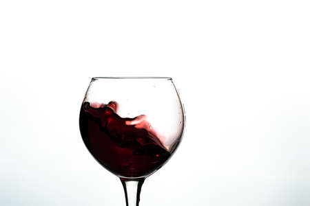 Red wine splash into glass on white background.の写真素材