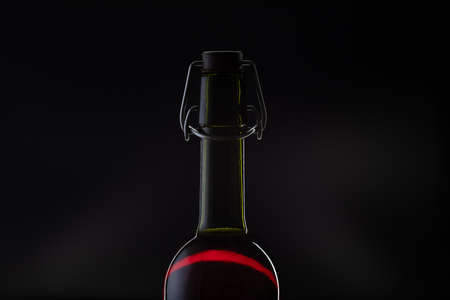Rose wine. Red wine in bottle and metal opener on cork. Dark background. Silhouetteの写真素材