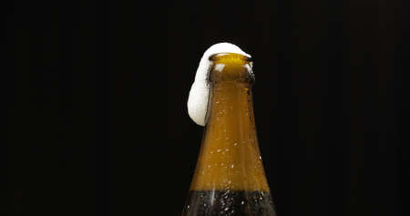 Opened cold bottle of beer. Cold beer on a black background. Craft beer in bottle with condensate and water drops. Close-up shotの写真素材