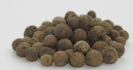 Black pepper. Peas with spices. Herbal spice, aromatic seasoning for food preparation and cooking, macro shot against a white backgroundの写真素材