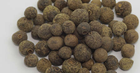 Black pepper. Peas with spices. Herbal spice, aromatic seasoning for food preparation and cooking, macro shot against a white backgroundの写真素材