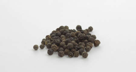 Black pepper. Peas with spices. Herbal spice, aromatic seasoning for food preparation and cooking, macro shot against a white backgroundの写真素材