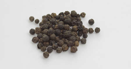 Black pepper. Peas with spices. Herbal spice, aromatic seasoning for food preparation and cooking, macro shot against a white backgroundの写真素材