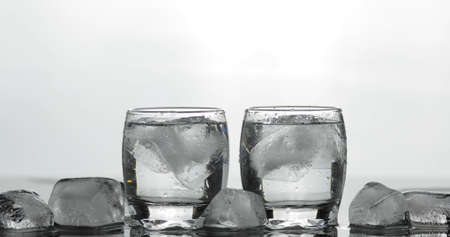 Shots of vodka in glasses. White background with ice cubes. Alcohol drink vodka tequilaの写真素材