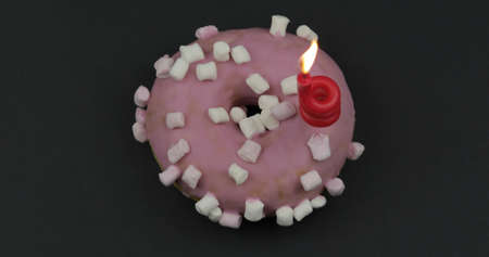 Delicious, tasty and fresh donut with festive candle. Top view. Bright and colorful sweet pink donut close-up macro shot on a black backgroundの写真素材