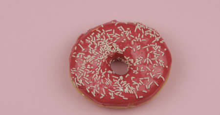 Delicious, tasty and fresh donut. Top view. Bright and colorful sprinkled sweet red donut close-up macro shot on a pink backgroundの写真素材