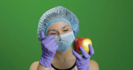 Female scientist makes a injection with a medicine syringe in apple. Concept of genetic engineering. Chroma key backgroundの写真素材