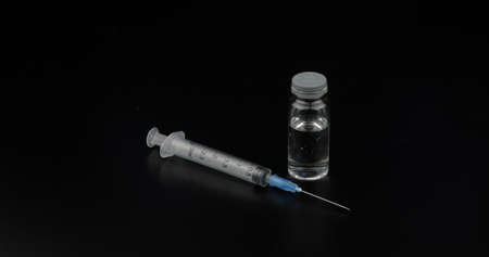syringe, ampoule with vaccination on black background.の写真素材