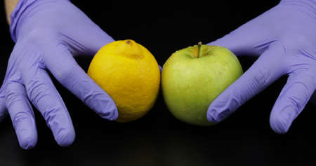 Doctors hands with apple and lemon on black background. Concept healthy life without pills, drugs....