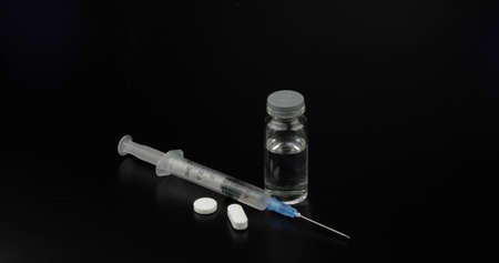 Pills, syringe and ampoule with vaccination on black background.の写真素材