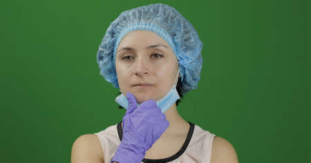 Close-up young doctor is thinking. Adult female medical worker in face mask holding chin on hand and looking thoughtful. Searching a right solution. Chroma key background. Green screenの写真素材