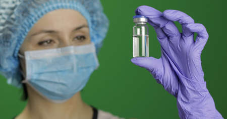 Female scientist holding ampoule in hand, new medication developing, vaccination. Concept of medicine and health improvement. Chroma key background. Green screenの写真素材