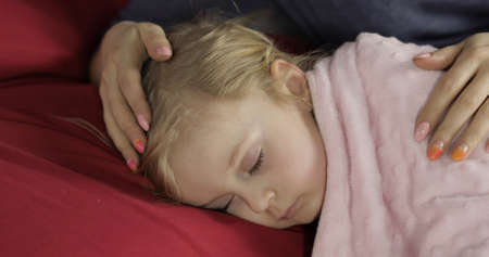 Young mother taking care of her little baby girl while she sleep. Girl sleeping on cozy bed at home....