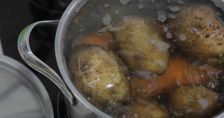 Hot boiling pan with vegetables potatoes and carrots. Cooking in a pan on the home kitchenの写真素材