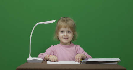 Girl drawing at the table. Education process. Happy three years old child. Cute girl smiling. Brown eyes. Green screen. Chroma Keyの写真素材