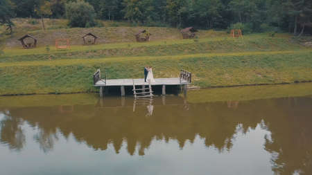 Groom with bride near lake in the park. Wedding couple. Man and woman in love. Aerial shotの写真素材