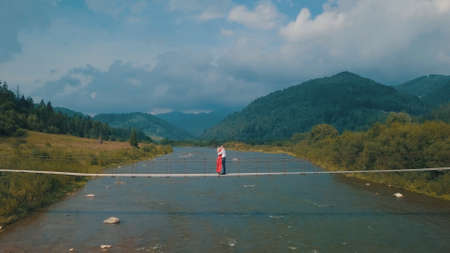 Young couple together. Man and woman in love on a bridge over the river. Aerial shot