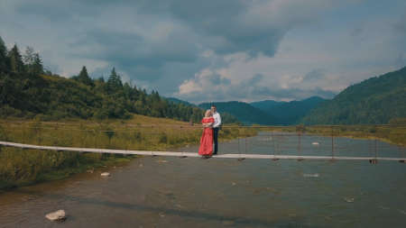 Young couple together. Man and woman in love on a bridge over the river. Aerial shotの写真素材