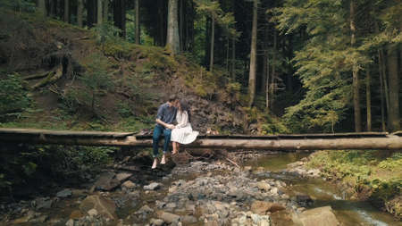 Young couple together. Man and woman in love on a bridge over the river in forest. Relationship and loveの写真素材