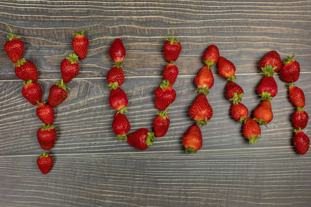 Strawberries making a word 'Yum' on the wooden table - close up.の写真素材