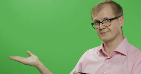 Caucasian man in glasses showing something. Guy in pink shirt. Place for your logo or text. Green...