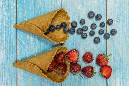 Berry and fruit ice cream. Flat lay various fresh fruits blueberry, strawberry in a waffle cone on...