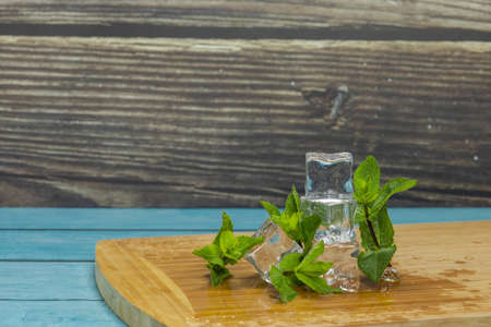 Ice cubes and fresh mint leaves isolated on wooden cutting board.の写真素材