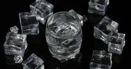 Shot of vodka with ice cubes against black background. Alcohol drink vodka tequila