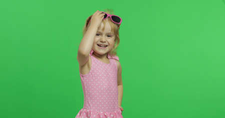 Child in pink swimsuit and sunglasses. Happy, pretty little blonde girl, 3-4 years old. Make faces and smile. Summer vacation concept. Green screen. Chroma Keyの写真素材