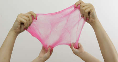 Woman and child hands playing with oddly satisfying pink slime on white background. Sticky gooey substance. Relax and inexplicably satisfying. Super viral trend on social media for antistress thingsの写真素材