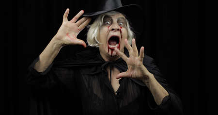 Old witch Halloween woman portrait. Elderly vampire woman with dripping blood on her mouth and eyes....