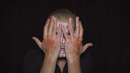 Clown Halloween man portrait. Close-up of crazy, evil clowns face with blood. White face makeup....