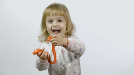 Child having fun making orange slime. Kid playing with hand made toy slime. Funny kid girl. Relax...