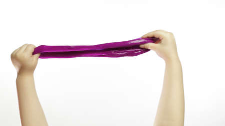 Child hands playing with oddly satisfying purple slime on white background. Sticky gooey substance. Relax and inexplicably satisfying. Super viral trend on social media for antistress thingsの写真素材
