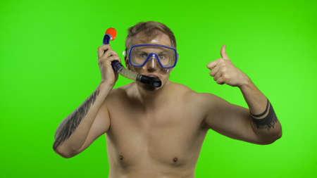 Emotional shirtless handsome sailor guy tourist in underwater swimming goggles mask and with breathing tube. Chroma key background. Muscular sailor man thumbs up. Concept of tourism, sea resortsの写真素材
