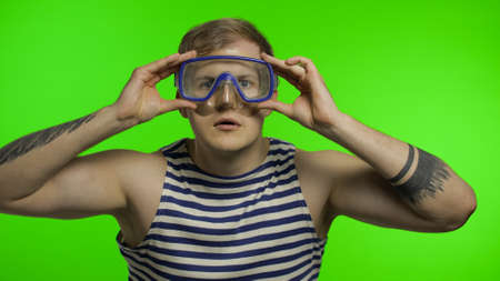 Emotional handsome guy tourist in underwater swimming goggles mask wear striped sailor shirt vest. Chroma key background. Muscular sailor man. Concept of tourism, sea resortsの写真素材