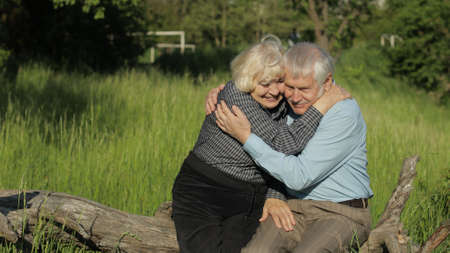 Senior old couple grandfather and grandmother sitting in park and hugs. Senior lifestyle family concept. Family time relaxの写真素材
