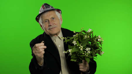 Elderly stylish grandfather caucasian mature man with bouquet of flowers and an engagement ring on...