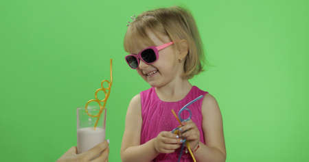 Girl in pink dress and sunglasses with milkshake cocktail. Happy four years old girl. Pretty little blonde child. Make faces. Place for your logo or text. Green screen. Chroma Keyの写真素材