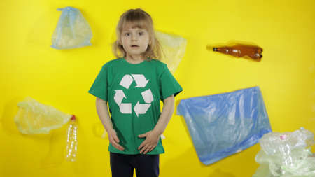 Girl activist volunteer in t-shirt with recycle logo. Background with bags, bottles. Save earth environment. Plastic trash nature pollutionの写真素材