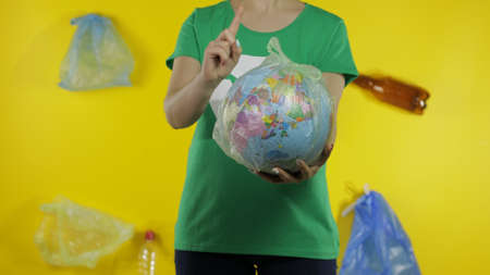 Unrecognizable woman girl activist in t-shirt with recycle logo with Earth globe in cellophane...