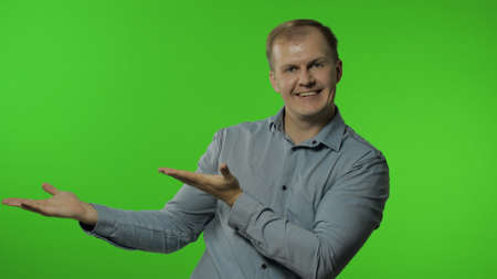 Amazed guy showing side advertising area. Looking shocked, pointing at blank wall with hands for your promotional text, logo. Portrait of man on chroma key background in studio. Sale, discountの写真素材