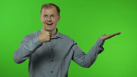 Amazed guy showing side advertising area. Looking shocked, pointing at blank wall with hands for...