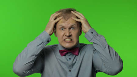 Man feeling crazy, stressed out, irritated about troubles, raising hands shouting desperately,...