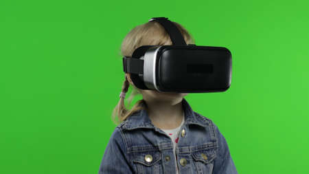 Young child girl using VR headset helmet to play game. Watching virtual reality 3d 360 video....